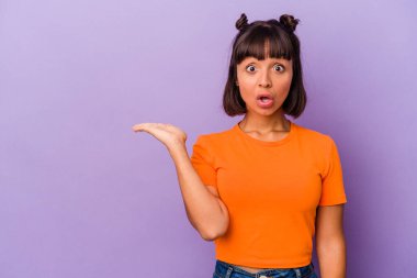 Mor arka planda izole edilmiş genç melez kadın avuç içlerindeki kopya alanını tutmaktan etkilenmiş..