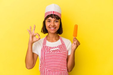 Genç melez dondurma üreticisi elinde dondurma tutan kadın sarı arka planda izole edilmiş neşeli ve kendinden emin..