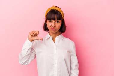 Pembe arka planda izole edilmiş genç melez kadın baş parmağını aşağı gösteriyor, hayal kırıklığı konsepti..