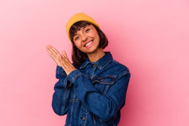 Pembe arka planda soyutlanmış genç melez bir kadın enerjik ve rahat hissediyor, ellerini ovuşturuyor..