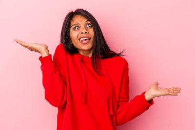 Pembe arka planda izole edilmiş genç Latin bir kadın. Kafası karışmış ve omuz silkiyor. Kopya alanını tutmak için..