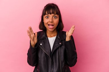 Pembe arka planda izole edilmiş genç melez bir kadın zaferi veya başarıyı kutluyor, şaşırıyor ve şok oluyor..