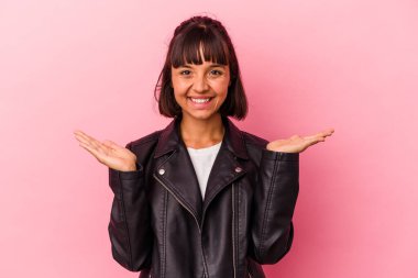 Pembe arka planda soyutlanmış genç melez kadın kollarıyla ölçeği yapıyor, mutlu ve kendinden emin hissediyor..