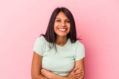 Genç Latin bir kadın pembe arka planda izole edilmiş gülüyor ve eğleniyor..