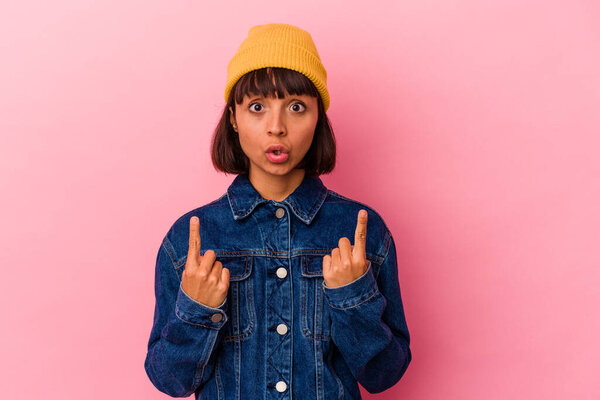 Молодая женщина смешанной расы изолированы на розовом фоне указывая вверх ногами с открытым ртом.