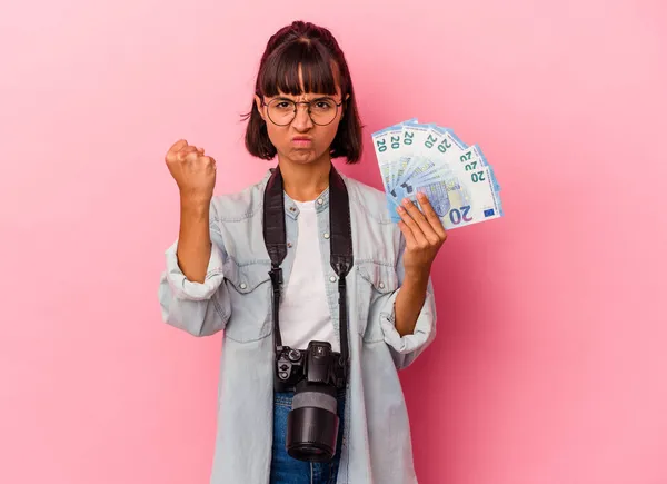 若い混合レース写真家の女性は カメラに拳を示すピンクの背景に隔離された法案を保持します 積極的な表情 — ストック写真