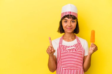 Genç melez dondurma üreticisi elinde dondurma tutan kadın sarı arka planda bir numarayı parmağıyla gösteriyor..