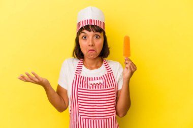 Sarı arka planda izole edilmiş dondurma tutan genç bir ırk dondurmacısı kadın omuzlarını silkeliyor ve gözleri açık..