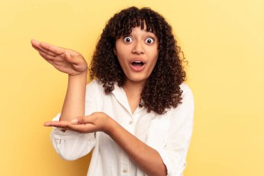 Sarı arka planda izole edilmiş genç bir ırk kadını elleri arasında bir kopya alanı tutarken şok ve şaşkınlık yaşadı..