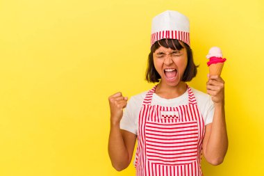 Genç melez dondurma üreticisi kadın dondurma tutuyor sarı arka planda izole edilmiş zafer kazandıktan sonra yumruk kaldırıyor, kazanan konsept..