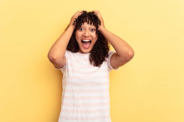 Genç melez kadın sarı arka planda izole edilmiş bağırıyor, çok heyecanlı, tutkulu, bir şeyden memnun..