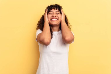 Sarı arka planda soyutlanmış melez bir kadın ellerini başının üstünde tutarak neşeyle gülüyor. Mutluluk kavramı.