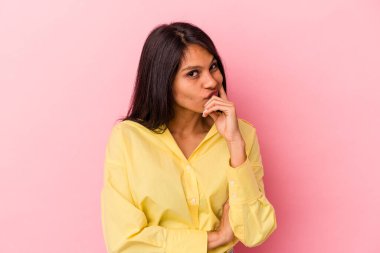 Pembe arka planda izole edilmiş genç Latin bir kadın. Bir strateji planlıyor, bir iş yolu düşünüyor..