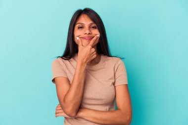 Mavi arka planda izole edilmiş genç Latin kadın iki seçenek arasında şüphe duyuyor.