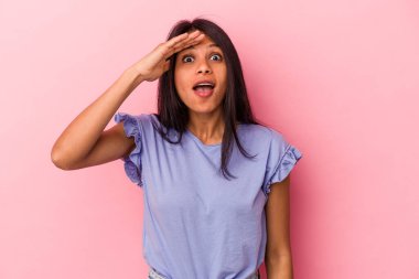 Pembe arka planda izole edilmiş genç Latin kadın yüksek sesle bağırıyor, gözleri açık ve elleri gergin tutuyor..