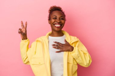 Genç Afrikalı Amerikalı kadın pembe arka planda izole edilmiş yemin ediyor, elini göğsüne koyuyor..