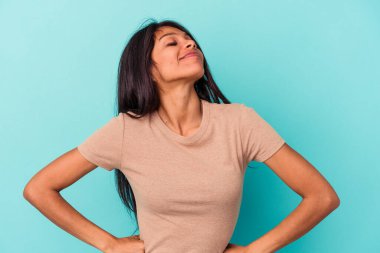 Mavi arka planda izole edilmiş genç Latin kadın hedeflere ve amaçlara ulaşma hayali kuruyor.