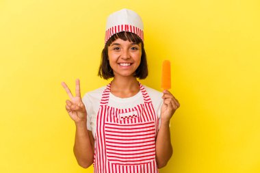 Küçük melez dondurma üreticisi kadın dondurma tutuyor sarı arka planda iki numarayı parmaklarıyla gösteriyor..