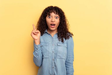 Sarı arka planda izole edilmiş, ağzı açık, üst tarafı gösteren genç melez bir kadın..