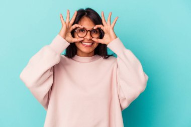 Mavi arka planda izole edilmiş genç latin kadın gözlerde sorun olmadığını gösteriyor.