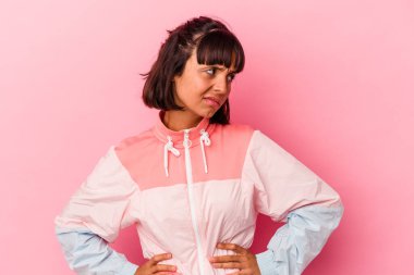 Pembe arka planda izole edilmiş genç melez kadın kafası karışmış, kuşkulu ve güvensiz hissediyor..