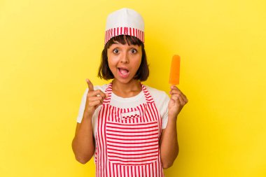 Genç melez dondurma üreticisi kadın elinde dondurma tutuyor sarı arka planda izole edilmiş bir şekilde bir fikri var, ilham verici bir kavram..