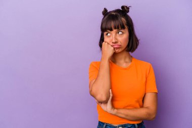 Mor arka planda soyutlanmış, üzgün ve dalgın hisseden, kopyalama alanına bakan genç melez bir kadın..