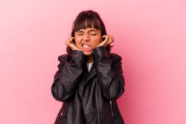 Genç melez kadın pembe arka planda izole edilmiş kulakları elleriyle kapatıyor..
