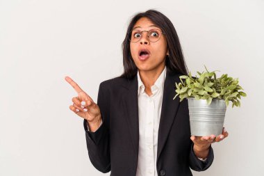 Beyaz arka planda izole edilmiş bitkileri tutan genç Latin kadın...