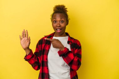 Sarı arka planda izole edilmiş genç Afrikalı Amerikalı kadın gülümseyerek beş numarayı parmaklarıyla gösteriyor..