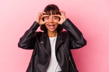 Pembe arka planda izole edilmiş genç melez kadın bir başarı fırsatı bulmak için gözlerini açık tutuyor..