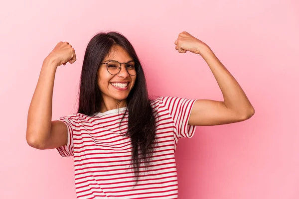Pembe arka planda izole edilmiş genç Latin kadın tasasız ve heyecanlı bir şekilde tezahürat yapıyor. Zafer konsepti.