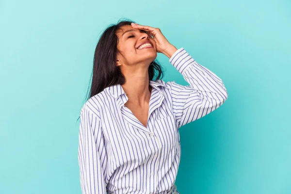 Genç Latin bir kadın mavi arka planda izole edilmiş gülerek, kaygısız, doğal duygular içinde..