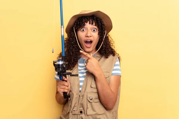 Young Mixed Race Fisherwoman Holding Rod Isolated Yellow Background Pointing — Stock Photo, Image