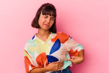 Genç melez kadın pembe arka planda izole edilmiş karaciğer ağrısı, karın ağrısı var..