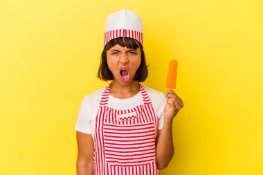 Genç melez dondurma üreticisi kadın elinde dondurma tutarken sarı arka planda izole edilmiş çok sinirli ve saldırgan çığlıklar atıyor..