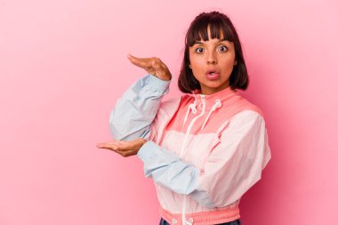 Pembe arka planda izole edilmiş genç bir ırk kadını elleri arasında bir kopya alanı tutarken şok ve hayret içinde..