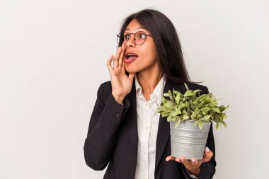 Beyaz arka planda bitkileri tutan genç Latin kadın gizli bir sıcak fren haberi veriyor ve kenara bakıyor.