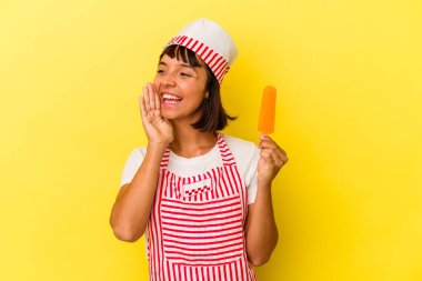 Sarı arka planda izole edilmiş dondurma tutan ve avuç içini açık tutan genç bir dondurma üreticisi kadın..