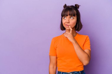 Mor arka planda izole edilmiş genç melez kadın şüpheli ve şüpheci bir ifadeyle yana bakıyor..