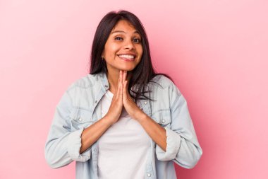 Pembe arka planda izole edilmiş genç Latin bir kadın. El ele tutuşup dua ediyor. Kendine güveniyor..