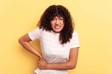 Sarı arka planda karaciğer ağrısı ve karın ağrısı çeken genç bir ırk kadını..