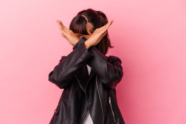 Genç melez kadın pembe arka planda izole edilmiş iki kolu çapraz tutuyor, inkar kavramı..