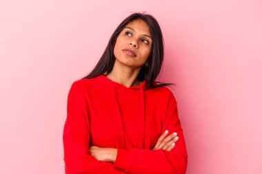 Pembe arka planda izole edilmiş genç Latin kadın hedeflere ve amaçlara ulaşmayı hayal ediyor.