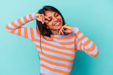 Mavi arka planda izole edilmiş genç Latin kadın özel bir günü kutluyor, atlıyor ve enerjiyle kollarını kaldırıyor..