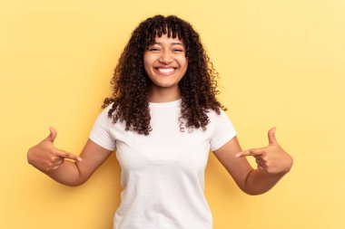 Sarı arka planda izole edilmiş genç melez kadın parmakları aşağıda, olumlu hisler içinde..