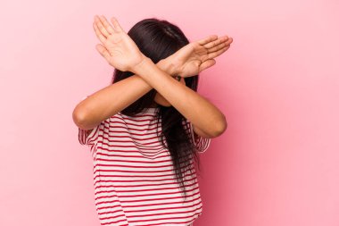 Pembe arka planda izole edilmiş genç Latin kadın iki kolu çapraz tutuyor, inkar kavramı.