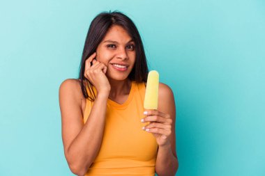 Dondurma tutan genç Latin kadın mavi arka planda izole edilmiş kulakları elleriyle kapatıyor..