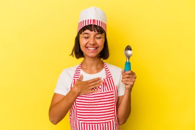 Genç melez dondurma üreticisi kadın sarı arka planda izole edilmiş dondurma tutuyor. Genç melez dondurma üreticisi kadın sarı arka planda izole edilmiş dondurma kepçesini tutuyor..