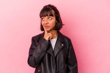 Pembe arka planda soyutlanmış genç melez bir kadın. Bir strateji planlıyor, iş yapmayı düşünüyor..